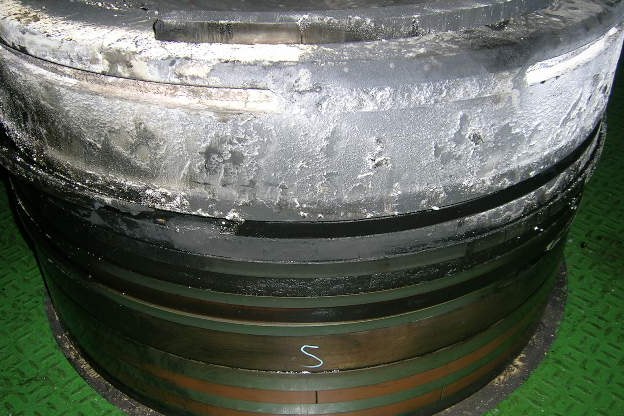 Piston removed from the engine, with thick grey ash deposits on the crown and top land