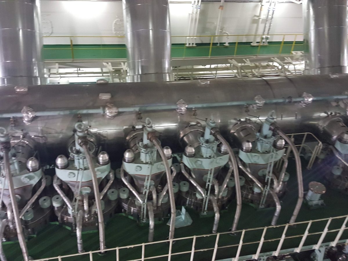 A large two-stroke engine seen from above: the row of cylinder covers with their fuel injectors, and the exhaust receiver behind