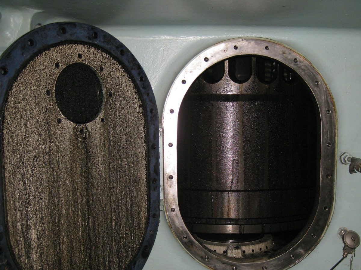 Open scavenge air box door with the piston ring pack and skirt visible inside